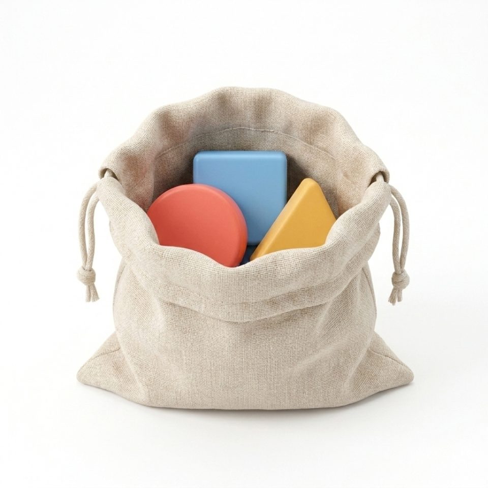 A small oatmeal cloth drawstring bag holding a coral circle, blue square and yellow triangle.