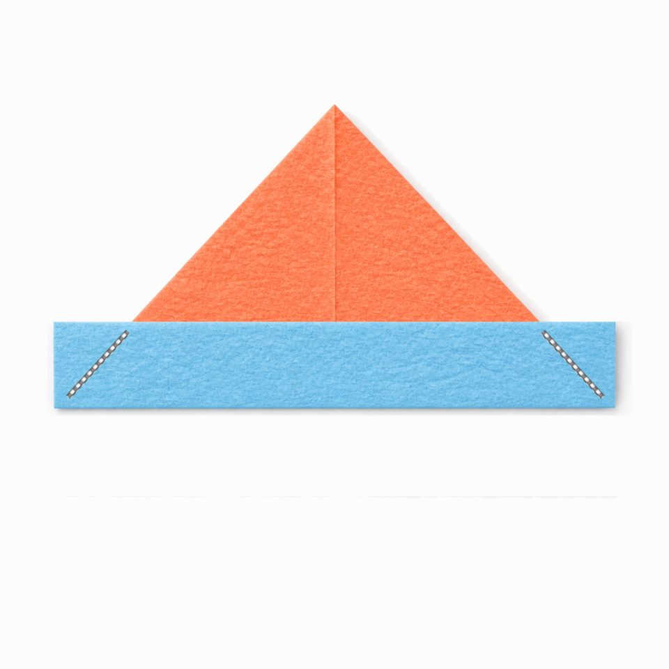 A coral paper hat with a blue bottom band and two dashed diagonal fold guides.