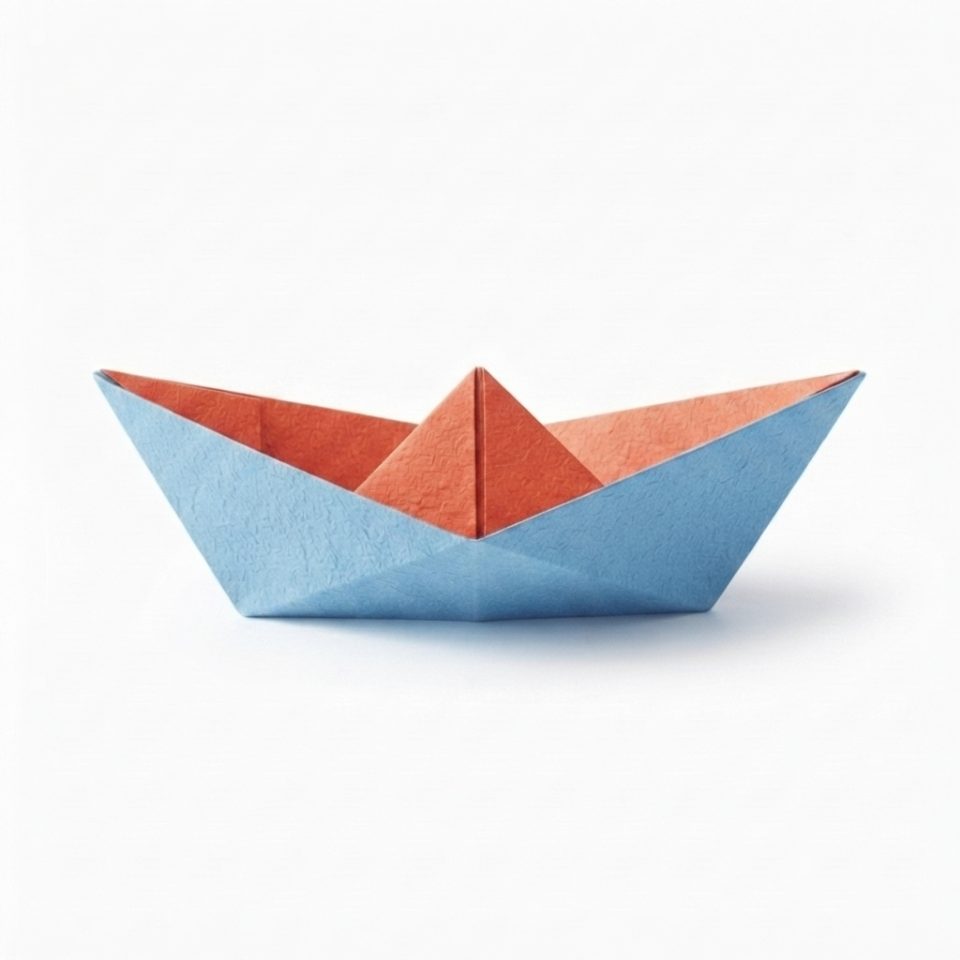 A finished coral and blue paper boat standing on a white background.